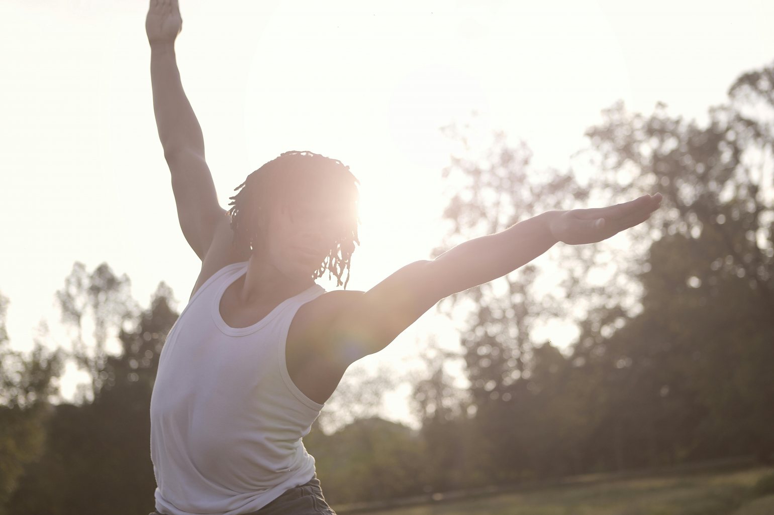 Man doing yoga in a park at sunrise